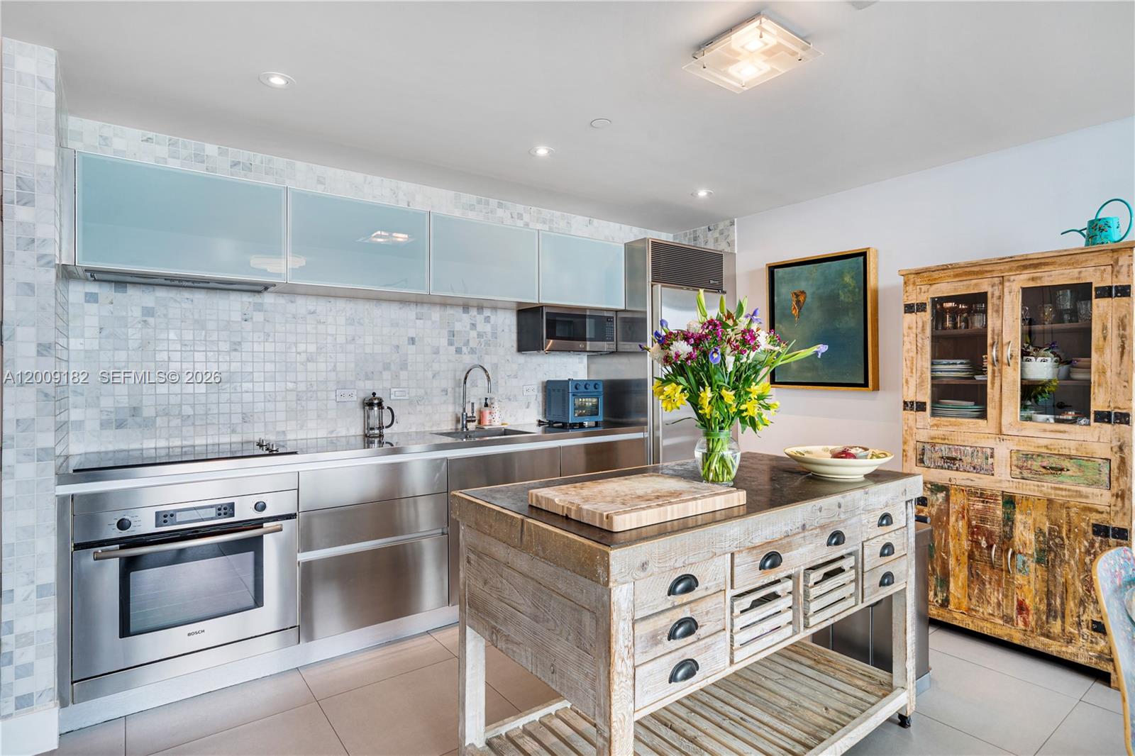 A modern kitchen features stainless steel cabinetry, a marble tile backsplash, and a rustic wooden island — 1040 Biscayne Blvd # 3607, Miami FL 33132, MIAMI, FL