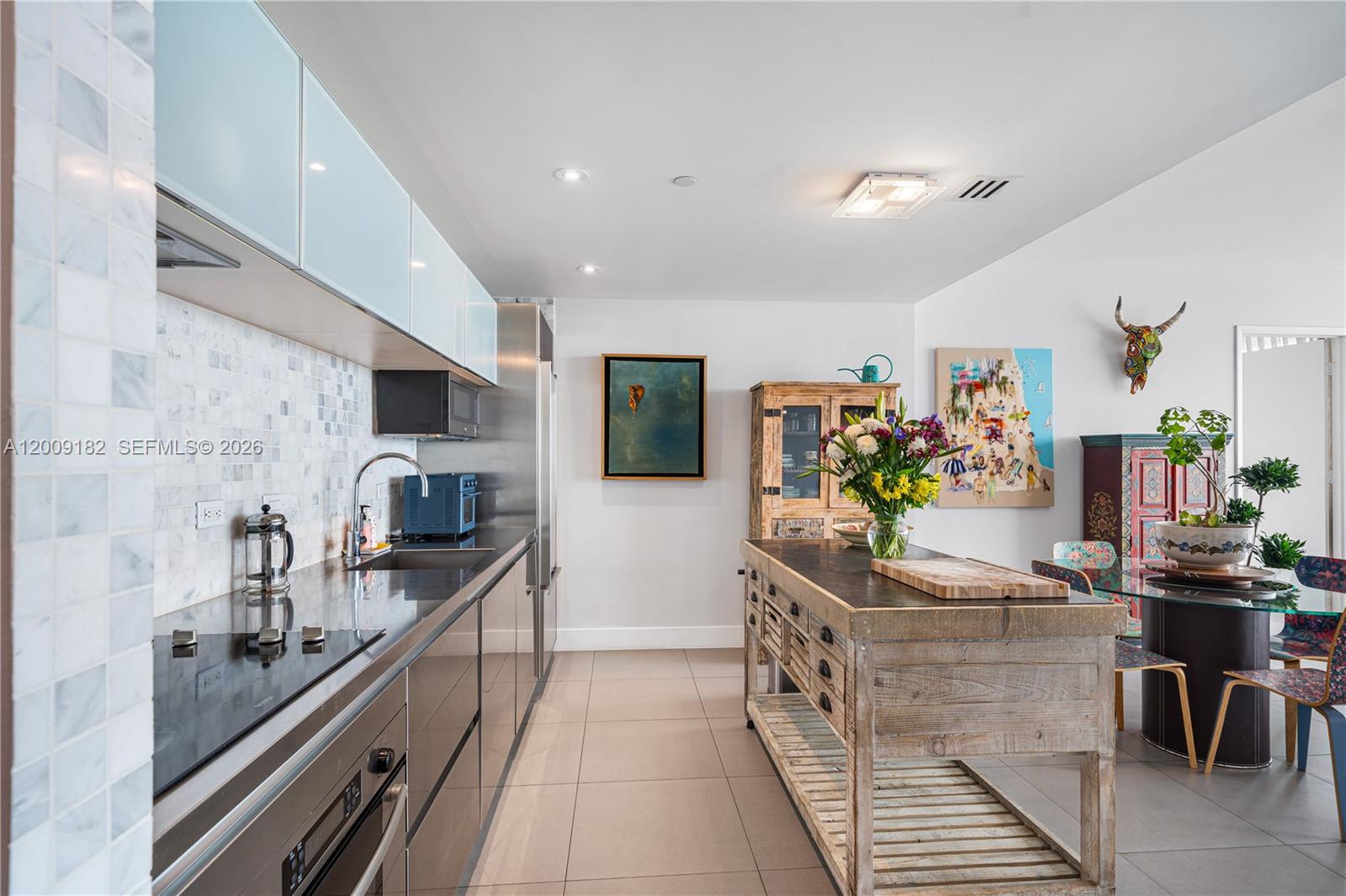 A modern kitchen features sleek dark cabinetry, a rustic wooden island, and a dining area — 1040 Biscayne Blvd # 3607, Miami FL 33132, MIAMI, FL