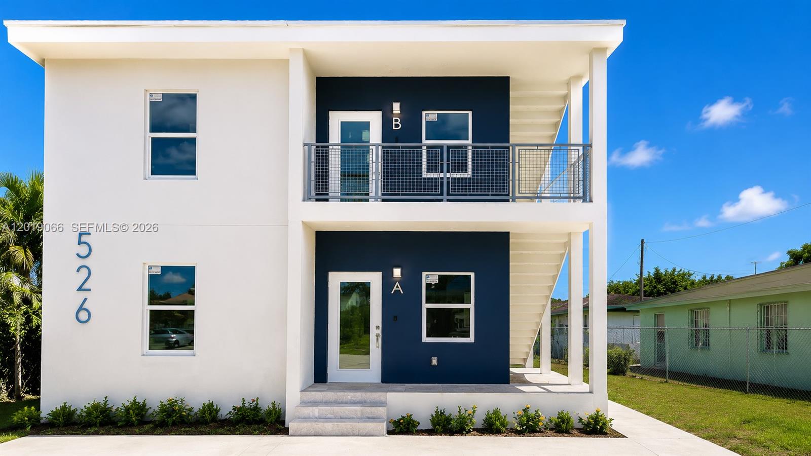 A two-story building features white stucco walls, dark blue accents, and an exterior staircase — 526 NW 6th St, Hallandale Beach FL 33009, HALLANDALE BEACH, FL