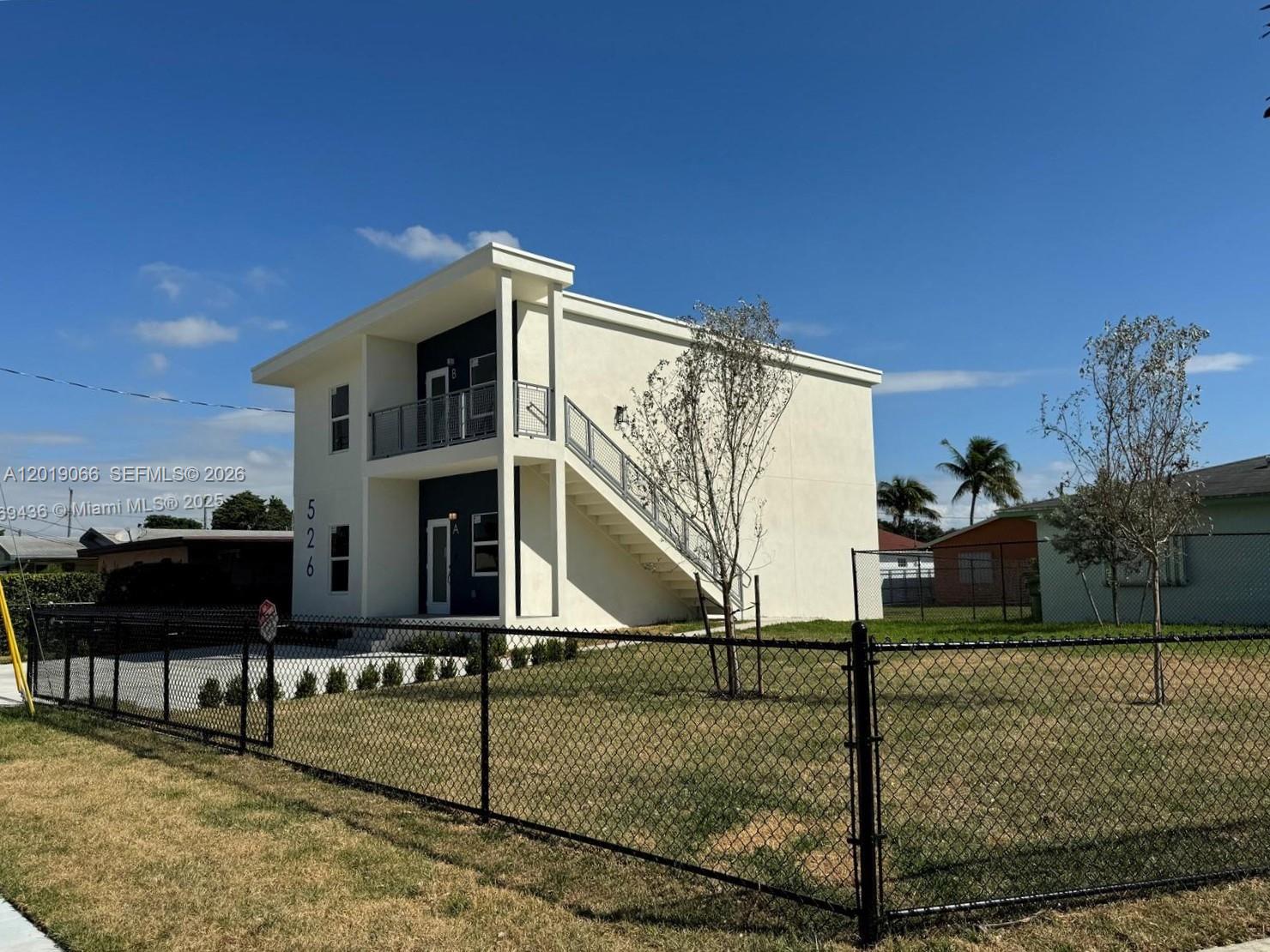 A two-story white building with an exterior staircase and a black chain-link fence — 526 NW 6th St, Hallandale Beach FL 33009, HALLANDALE BEACH, FL