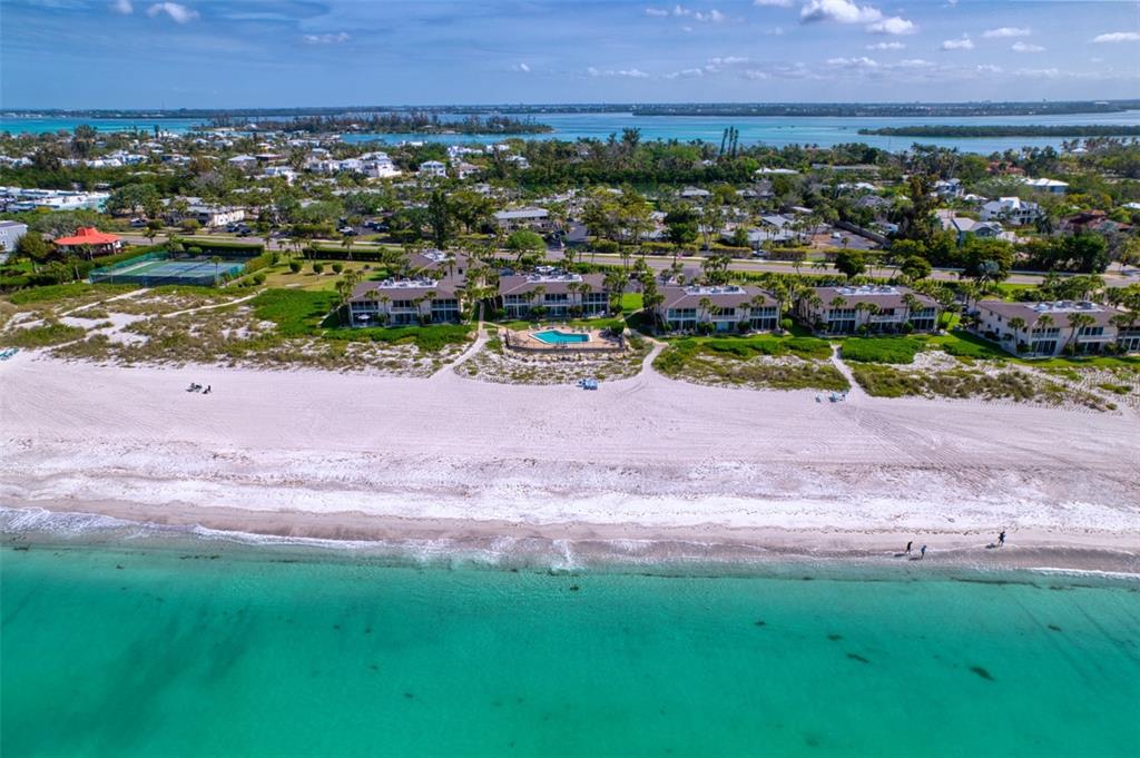 An aerial view shows beachfront condominiums with a pool along a sandy coastline — 6701 GULF OF MEXICO DRIVE UNIT 332, LONGBOAT KEY, FL