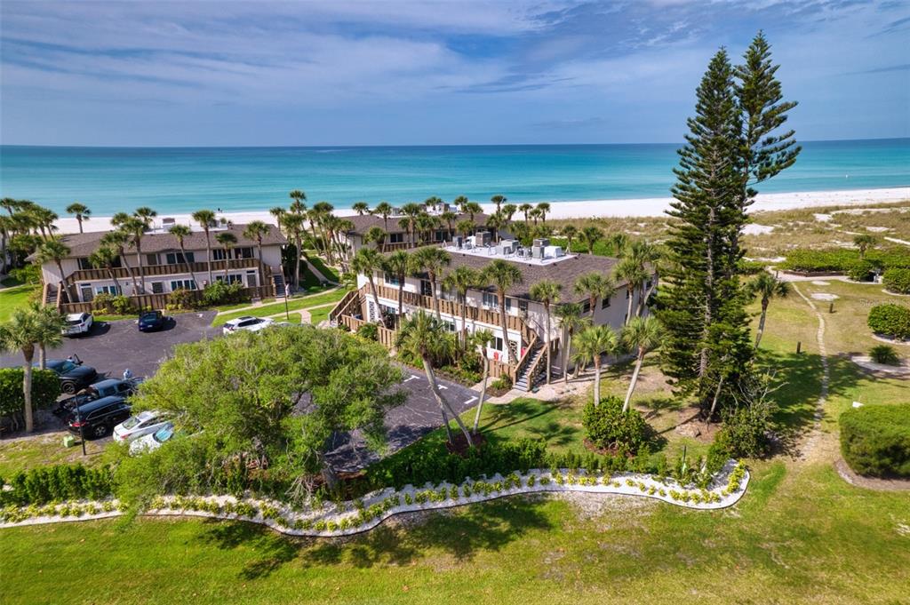 An aerial view shows two-story beachside apartment buildings with parking lots and palm trees — 6701 GULF OF MEXICO DRIVE UNIT 332, LONGBOAT KEY, FL