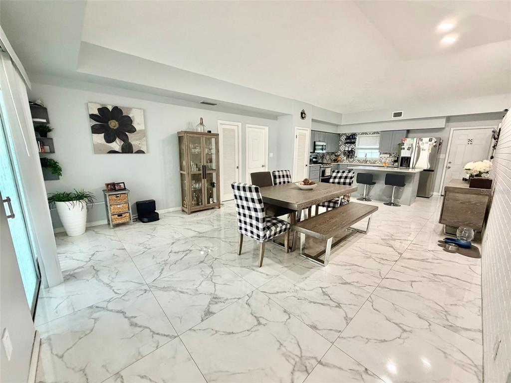 A dining area with a table and bench sits adjacent to an open-concept kitchen — 6004 MEMORIAL HIGHWAY, TAMPA, FL