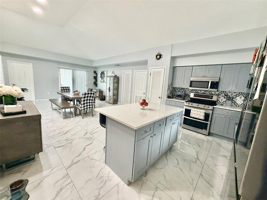 A kitchen with light gray cabinets, a white quartz island, and white marble-patterned tile flooring — 6004 MEMORIAL HIGHWAY, TAMPA, FL