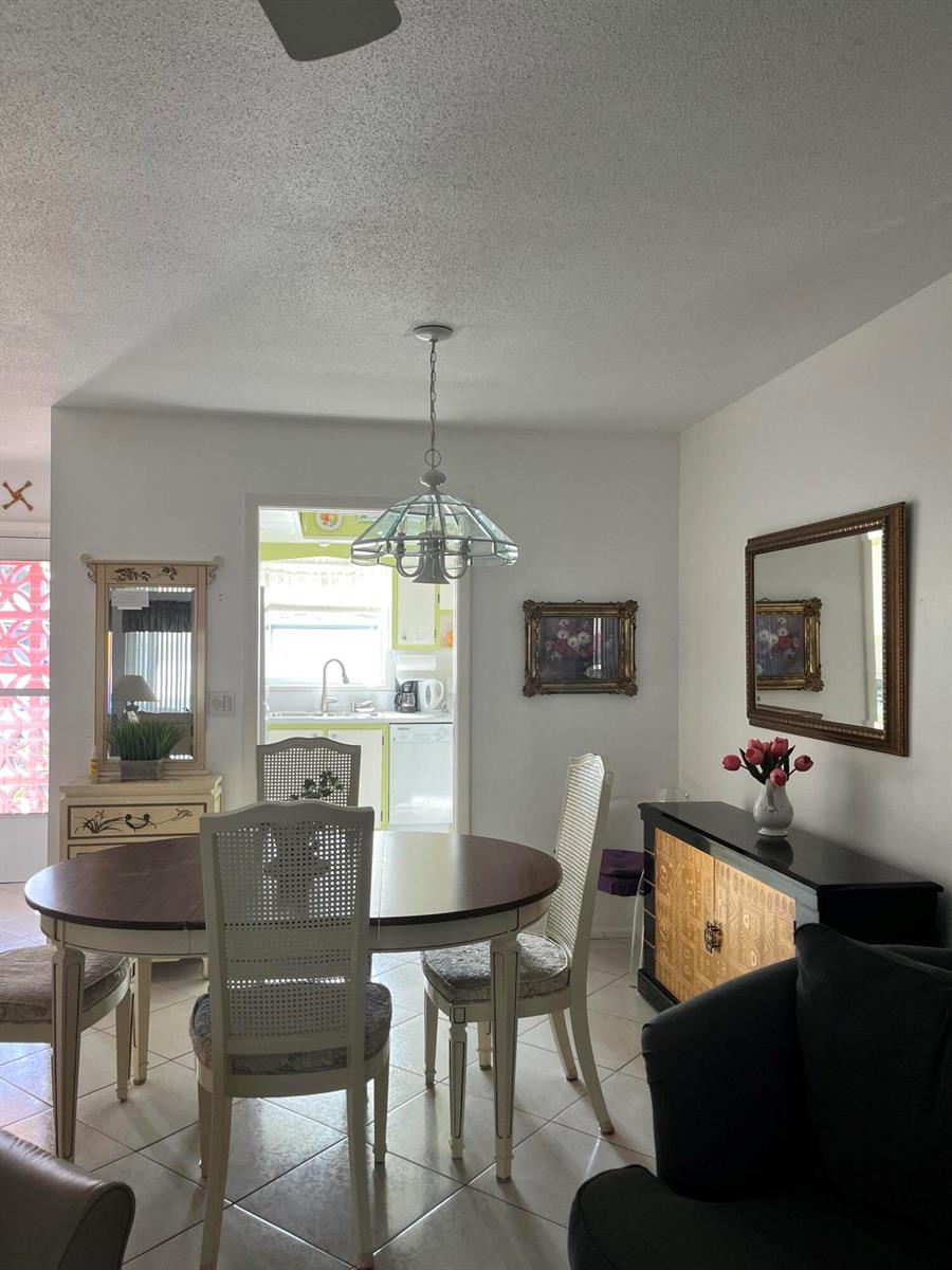 A dining area features a round wooden table, four chairs, a sideboard, and a chandelier — 2980 Crosley Drive E # F, West Palm Beach FL 33415, WEST PALM BEACH, FL