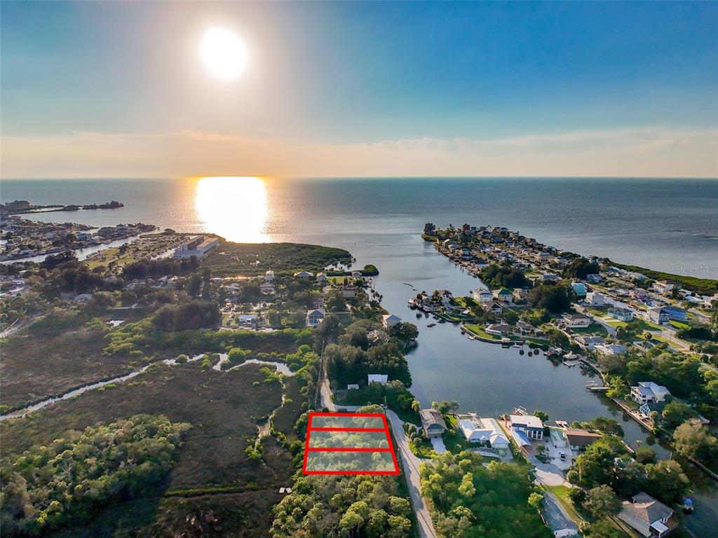 An aerial view shows a rectangular plot of land outlined in red near a waterway — lot 12 NOWIKI AVENUE, HUDSON, FL