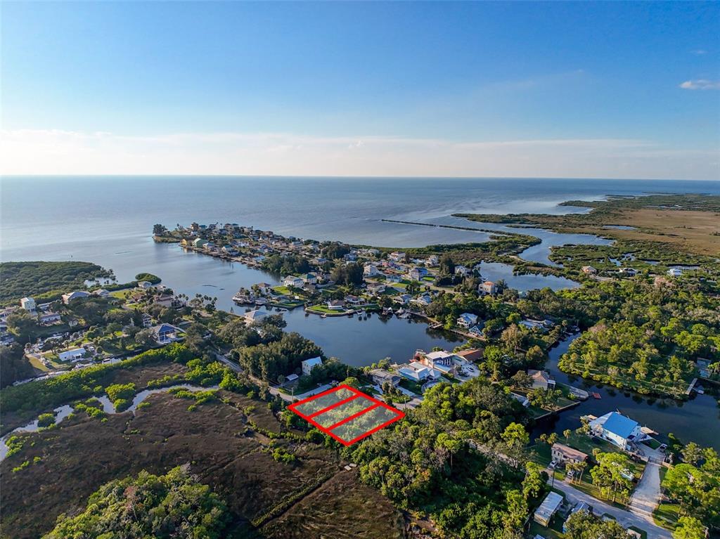 An aerial view shows three adjacent vacant lots outlined in red near a coastal waterway — lot 12 NOWIKI AVENUE, HUDSON, FL