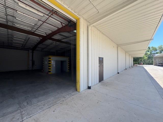 An open warehouse bay features a concrete floor, metal walls, and a small interior office — 2251 TOPLINE WAY UNIT 5, BROOKSVILLE, FL