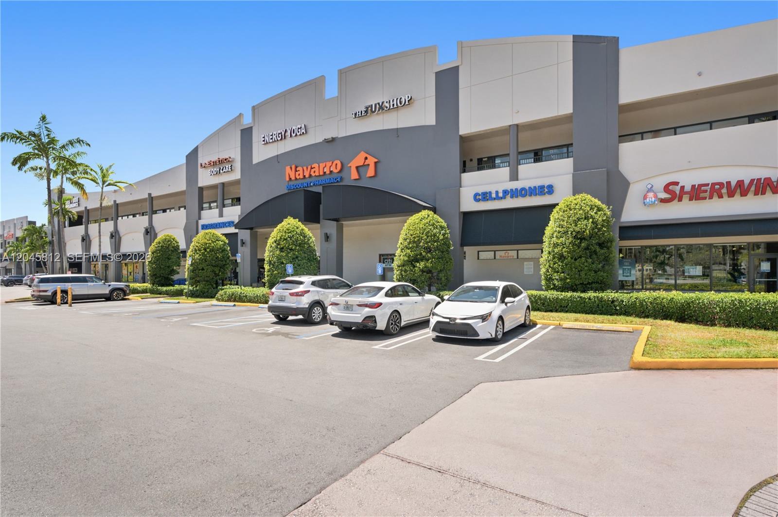 An exterior view of a commercial strip mall with several storefronts and a parking lot — 11402 NW 41st St # 207, Doral FL 33178, DORAL, FL