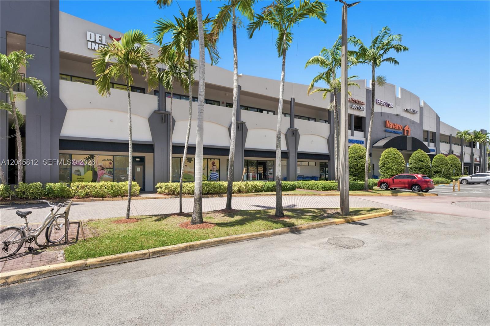 A multi-story commercial building exterior features palm trees, a parking lot, and storefront signage — 11402 NW 41st St # 207, Doral FL 33178, DORAL, FL