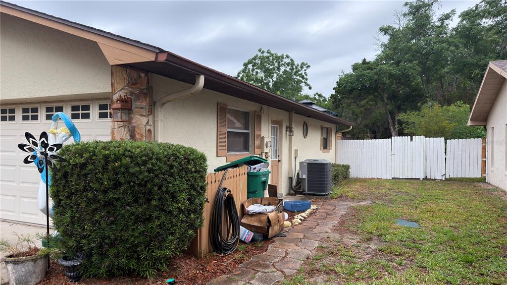 The side exterior of a house features a garage, a stone path, and a fence — 4076 S OAKHURST DRIVE, HOMOSASSA, FL