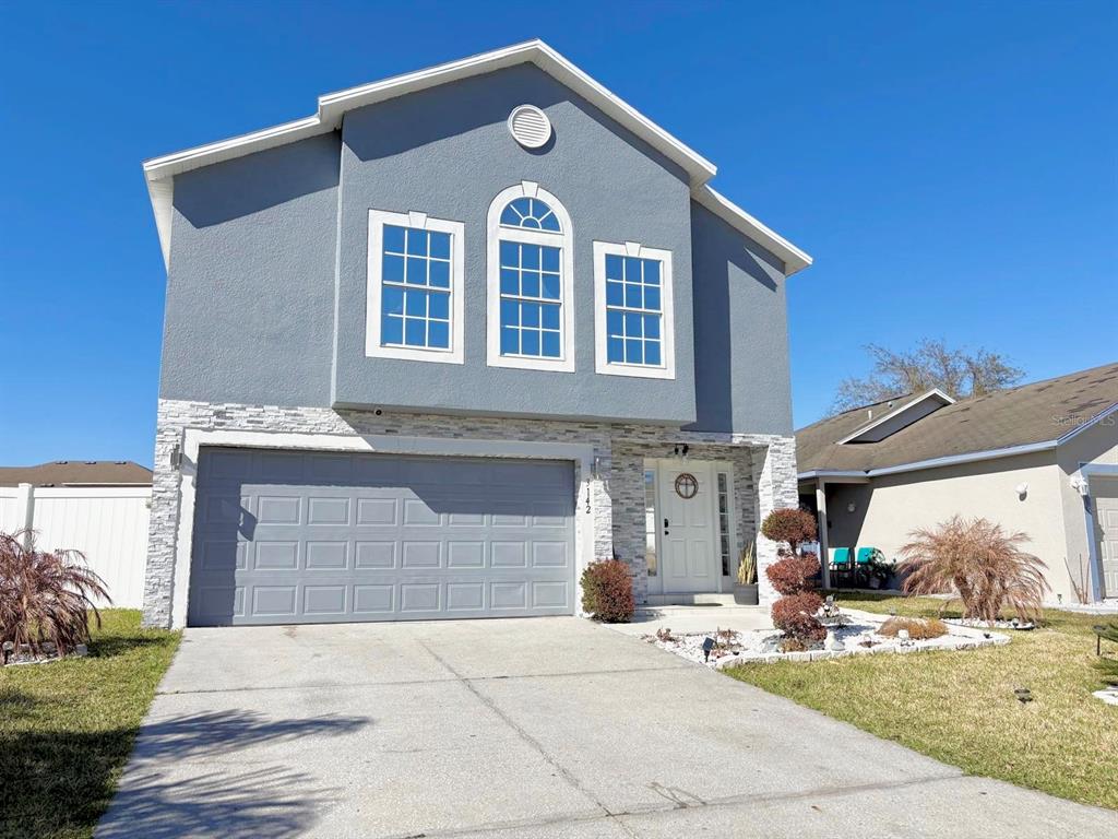 A two-story house with a gray stucco exterior, stone accents, and a two-car garage — 3142 WHISPERING TRAILS STREET, WINTER HAVEN, FL