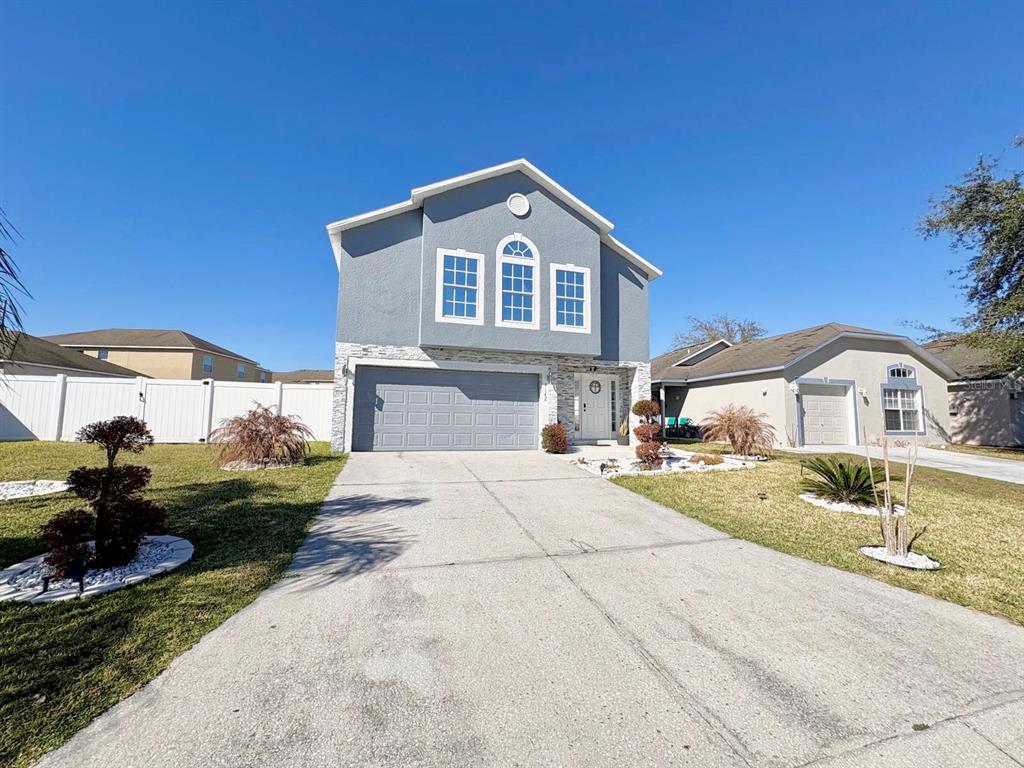 A two-story gray house with a stone facade, a two-car garage, and a concrete driveway — 3142 WHISPERING TRAILS STREET, WINTER HAVEN, FL