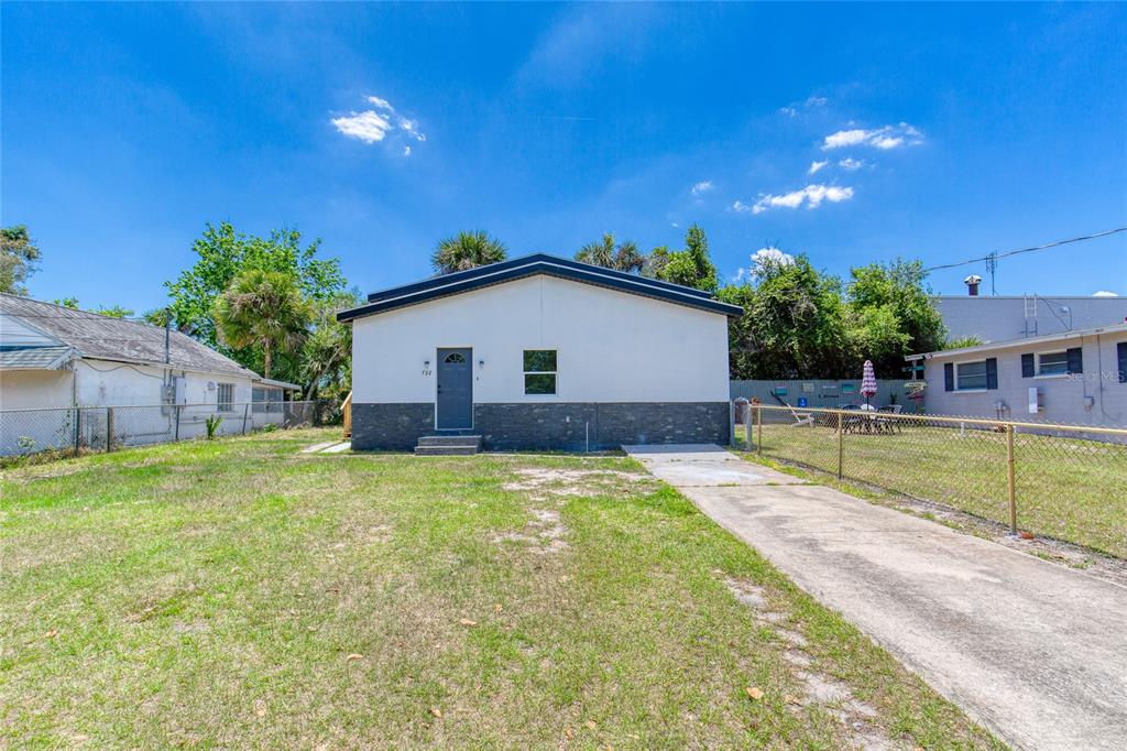 A single-story house with a white facade and dark stone base sits behind a lawn — 732 AVONDALE AVENUE, DAYTONA BEACH, FL