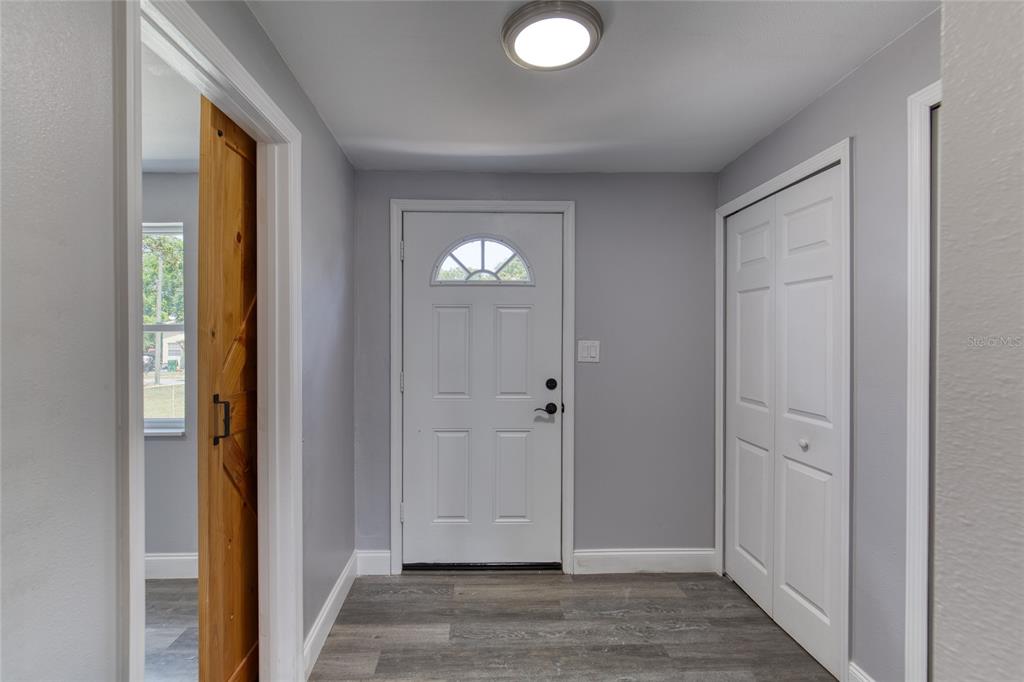 An entryway features gray walls, wood-look flooring, a white front door, and a sliding barn door — 732 AVONDALE AVENUE, DAYTONA BEACH, FL
