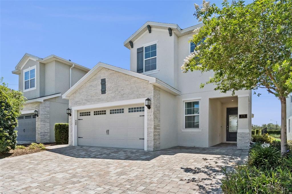 A two-story suburban house with a stone-accented garage and a paved driveway — 276 SOUTHFIELD STREET, KISSIMMEE, FL