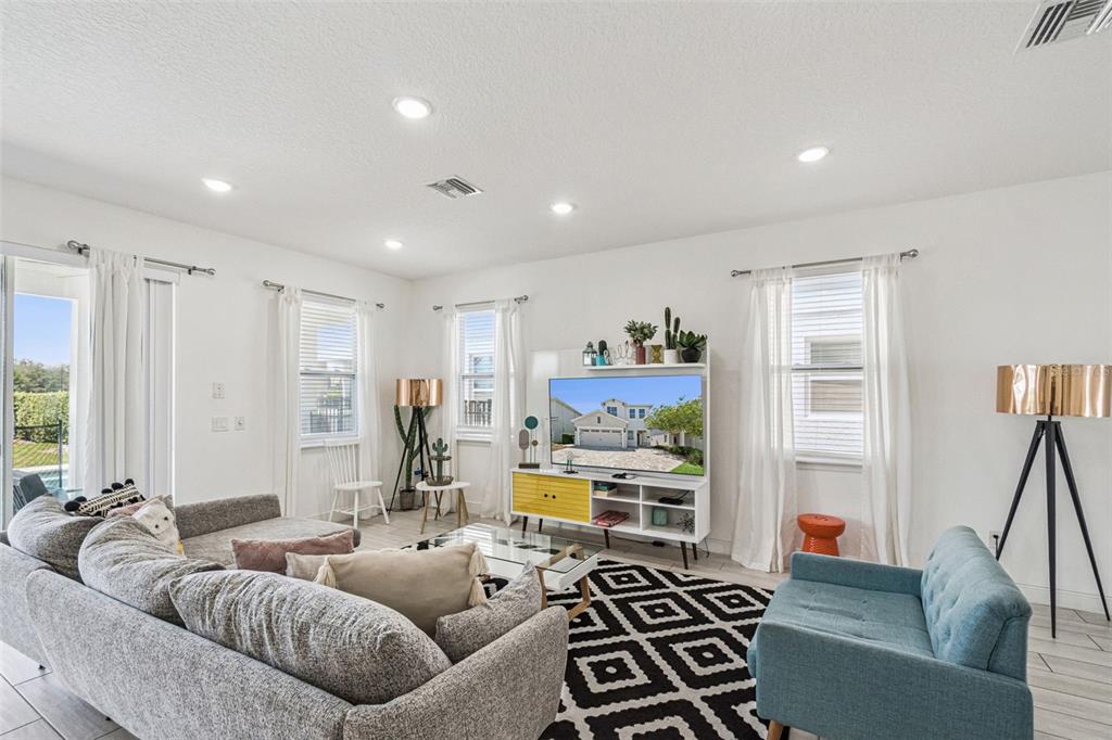 A living room features a gray sectional, a blue armchair, and a patterned area rug — 276 SOUTHFIELD STREET, KISSIMMEE, FL