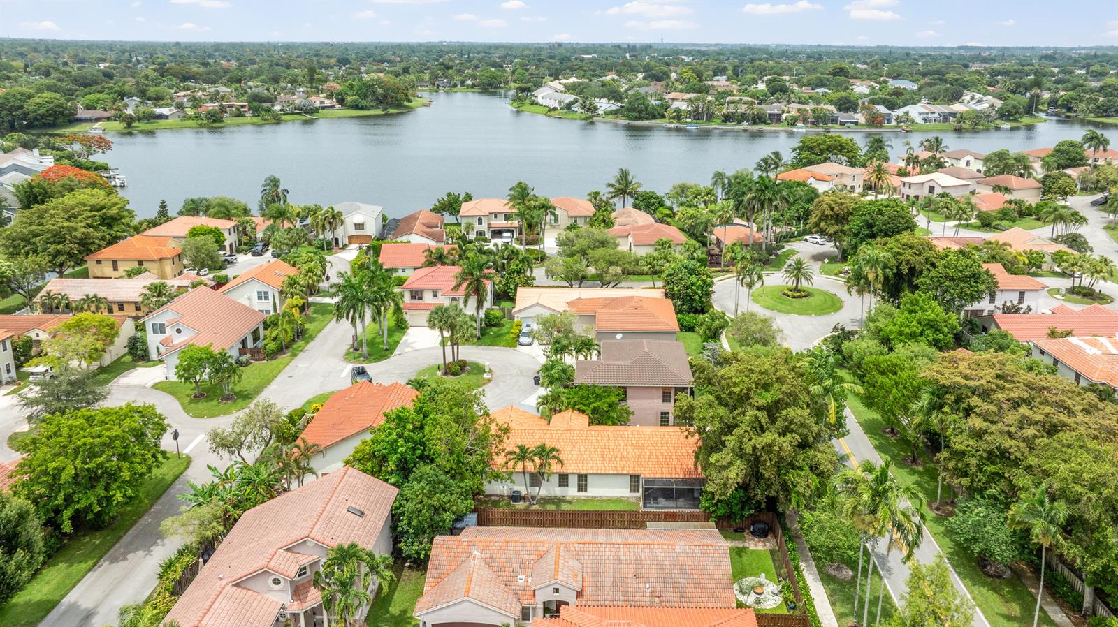 An aerial view of a suburban neighborhood featuring houses with terracotta roofs near a lake — 1763 Harborside Circle, Wellington FL 33414, WELLINGTON, FL