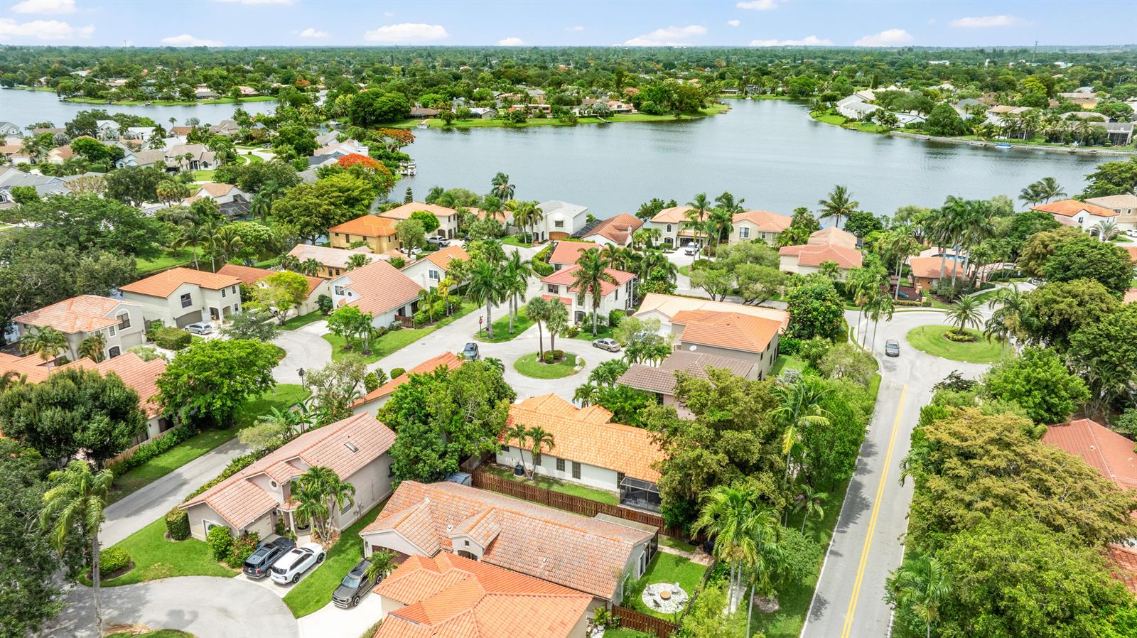 An aerial view shows a residential neighborhood with houses featuring orange tile roofs near a lake — 1763 Harborside Circle, Wellington FL 33414, WELLINGTON, FL