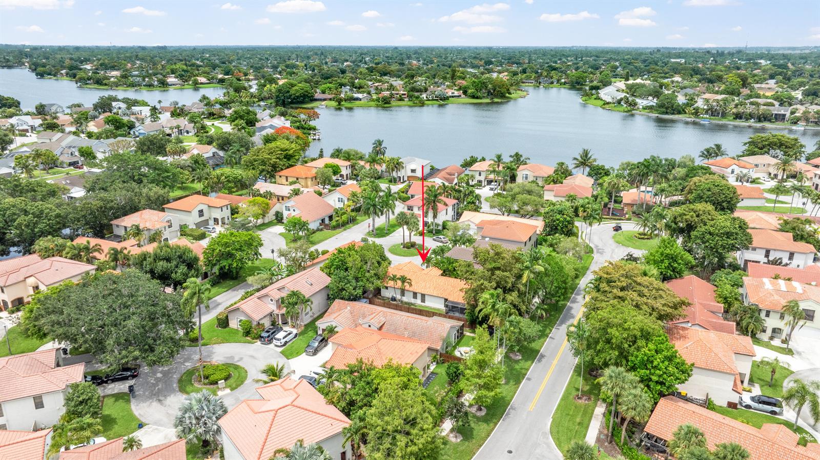 An aerial view shows a residential neighborhood with houses featuring orange tile roofs near a lake — 1763 Harborside Circle, Wellington FL 33414, WELLINGTON, FL