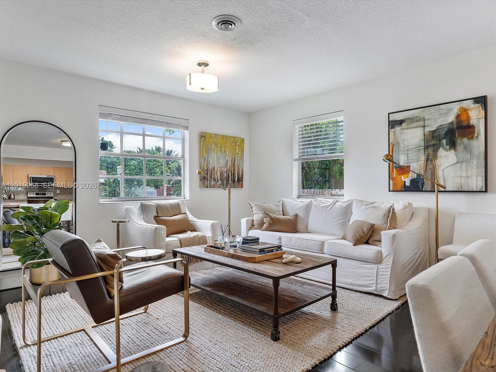 A living room features a white sofa, leather armchair, wooden coffee table, and large windows — 200 SW 2nd Ave, Hallandale Beach FL 33009, HALLANDALE BEACH, FL