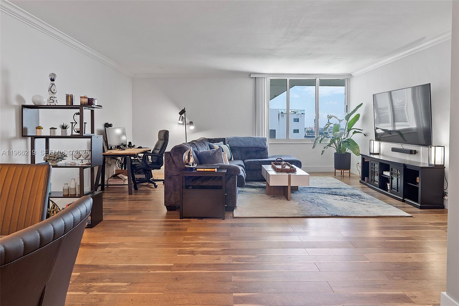 A living room features a sectional sofa, a desk area, and a television on wood flooring — 1200 West Ave, Miami Beach FL 33139, MIAMI BEACH, FL