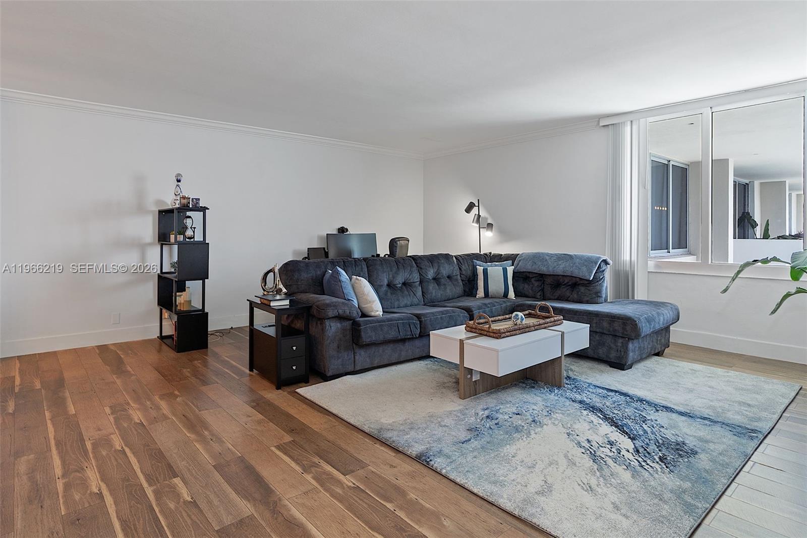 A living room features a dark sectional sofa, a white coffee table, and wood flooring — 1200 West Ave, Miami Beach FL 33139, MIAMI BEACH, FL