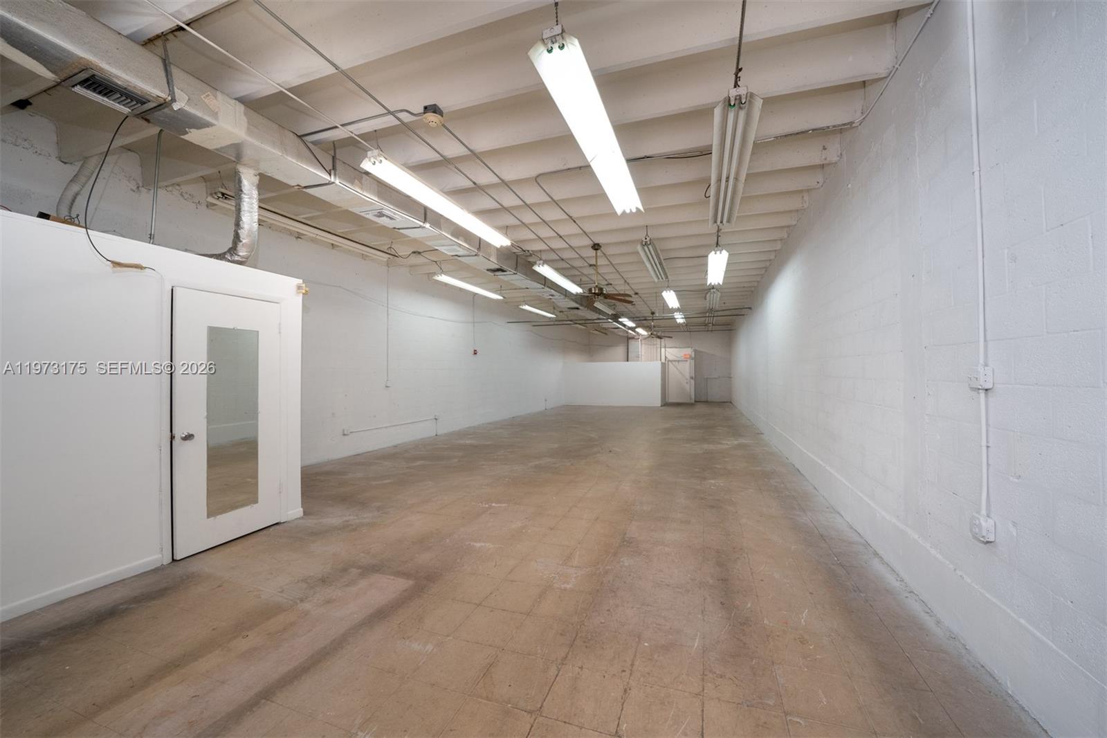 An empty industrial space features white block walls, a concrete floor, and exposed ceiling lights — 1852 NW 20th St # 1852, Miami FL 33142, MIAMI, FL