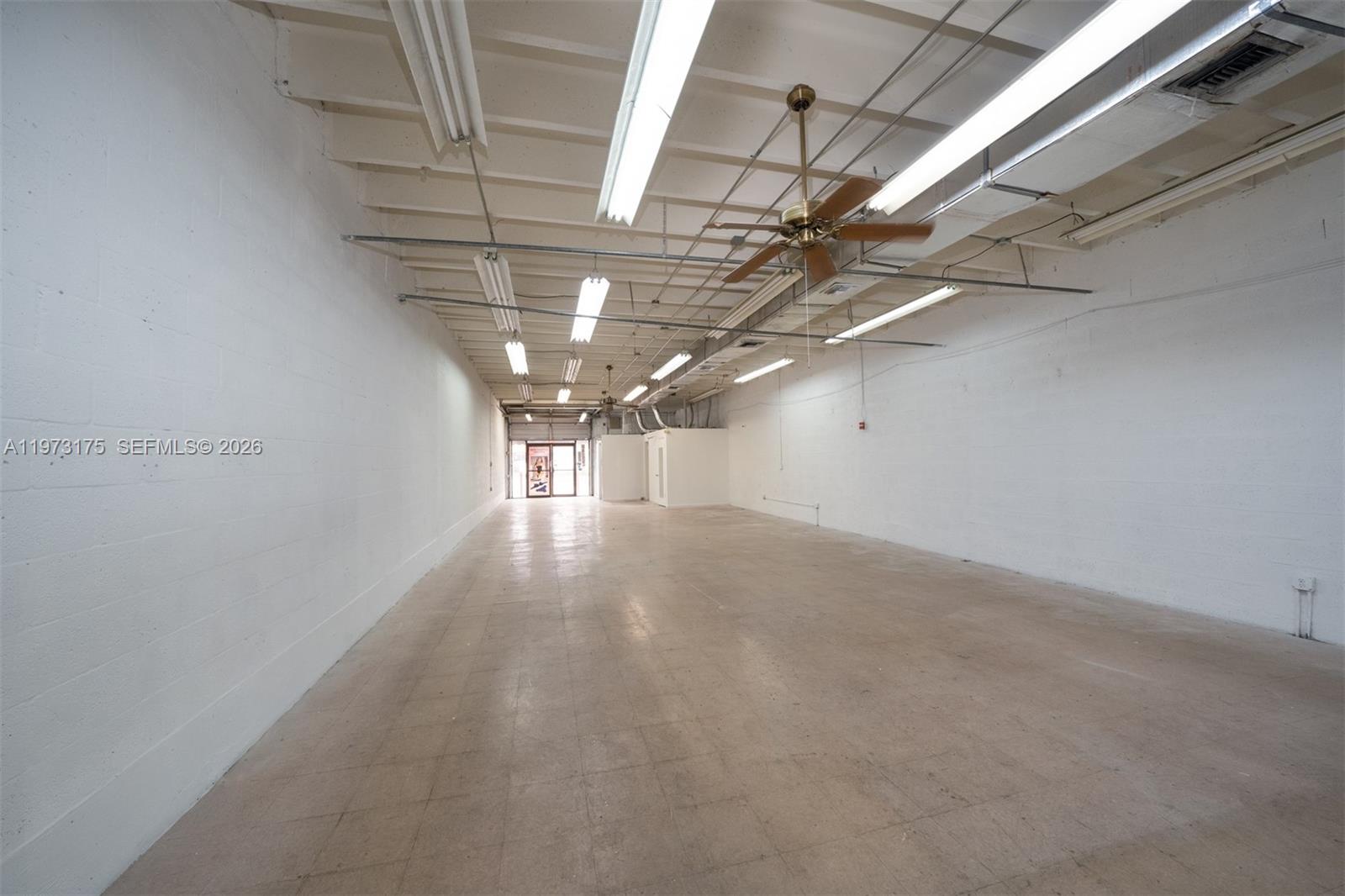 An empty, rectangular commercial space features white concrete block walls, a tiled floor, and exposed ceiling lights — 1852 NW 20th St # 1852, Miami FL 33142, MIAMI, FL