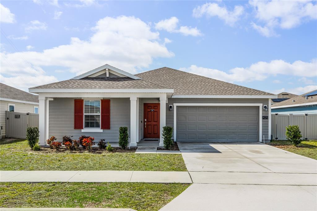A single-story house with gray siding, a red front door, and a two-car garage — 425 N ANDREA CIRCLE, HAINES CITY, FL