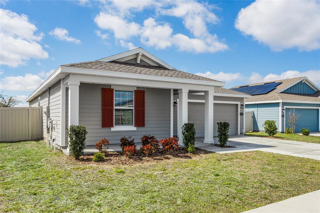 A gray single-story house with a covered porch, red shutters, and an attached garage — 425 N ANDREA CIRCLE, HAINES CITY, FL