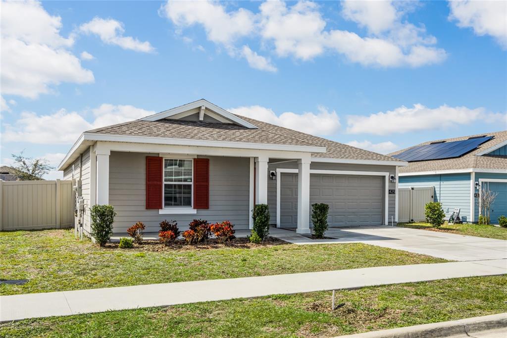 A single-story gray house with red shutters, a front porch, and a concrete driveway — 425 N ANDREA CIRCLE, HAINES CITY, FL