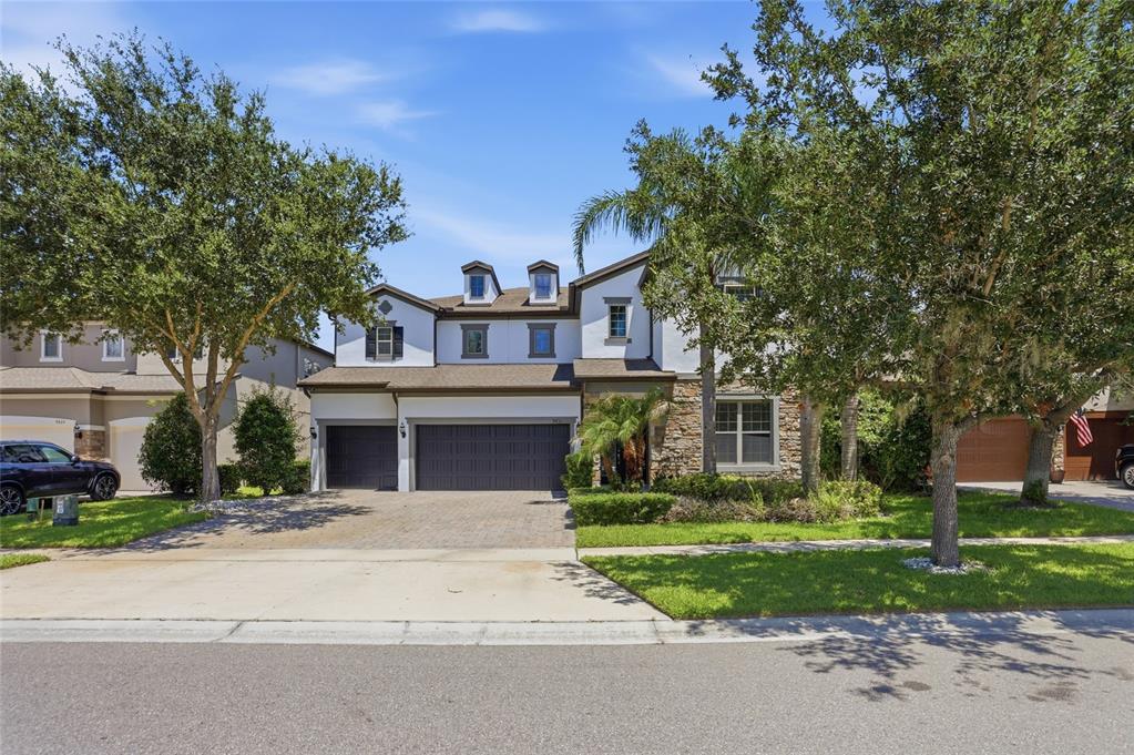 A two-story suburban house with a stone facade, a three-car garage, and dormer windows — 9431 ROYAL ESTATES BOULEVARD, ORLANDO, FL