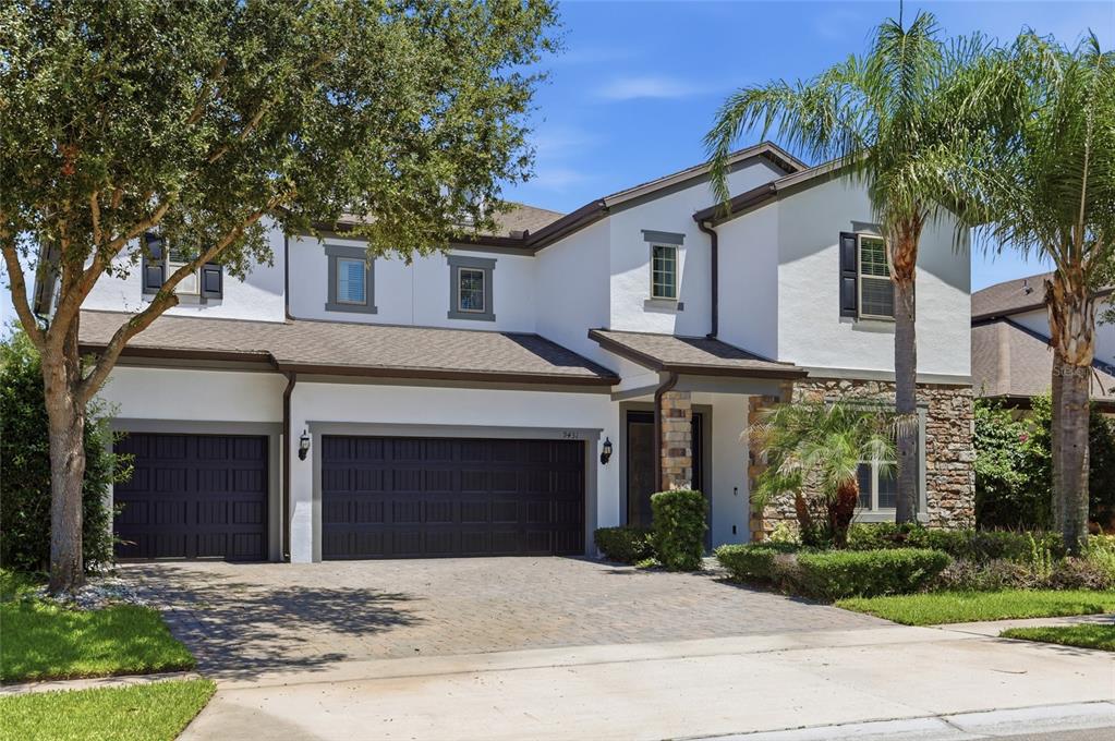 A two-story house with a three-car garage, stone accents, and a paved driveway — 9431 ROYAL ESTATES BOULEVARD, ORLANDO, FL