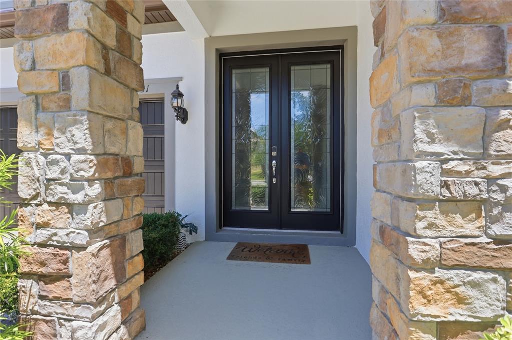 A stone-columned entryway features a double front door with glass panels and a welcome mat — 9431 ROYAL ESTATES BOULEVARD, ORLANDO, FL