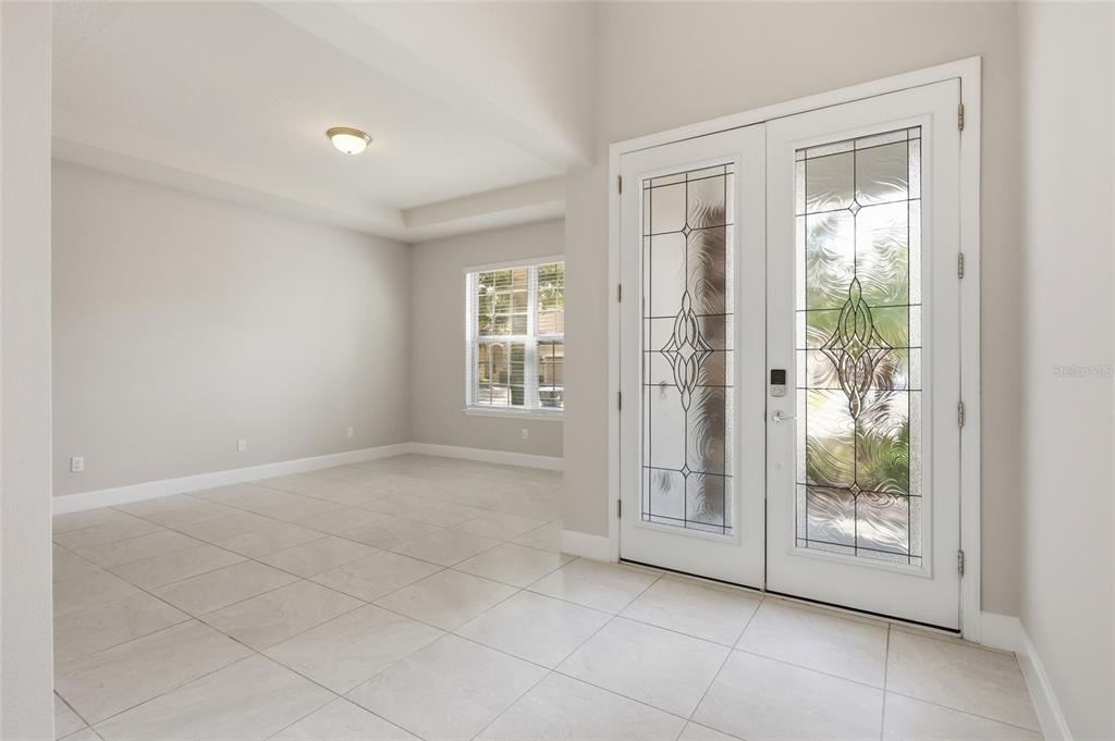 An entryway with light tile flooring, neutral walls, and double glass-paneled front doors — 9431 ROYAL ESTATES BOULEVARD, ORLANDO, FL