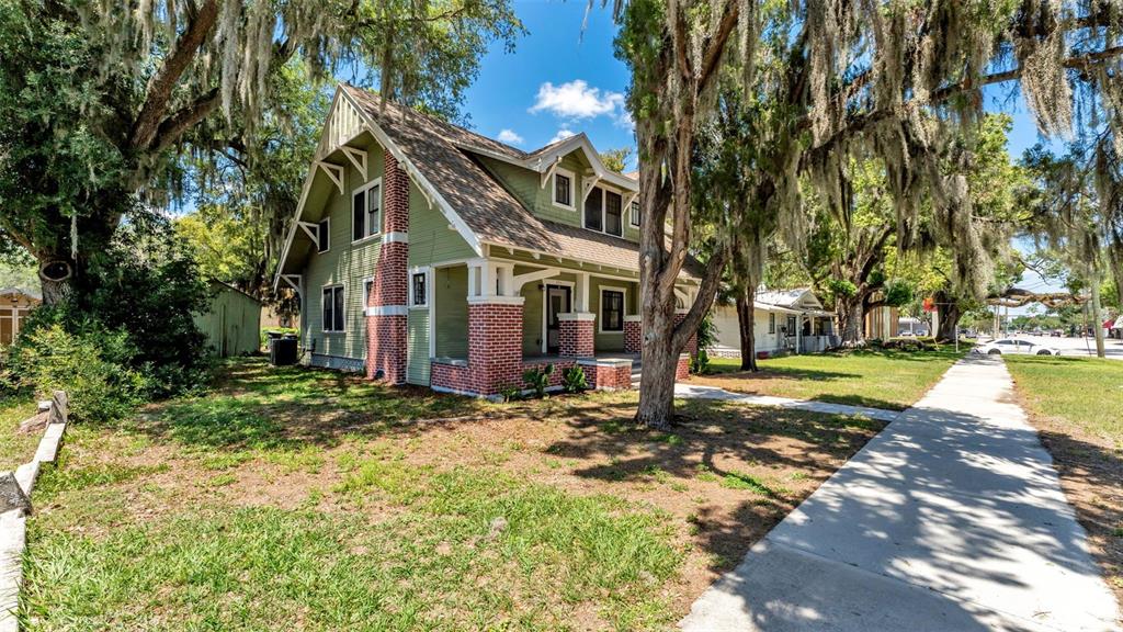 A two-story green house with brick accents and a front porch sits near a sidewalk — 355 S BROADWAY AVENUE, BARTOW, FL
