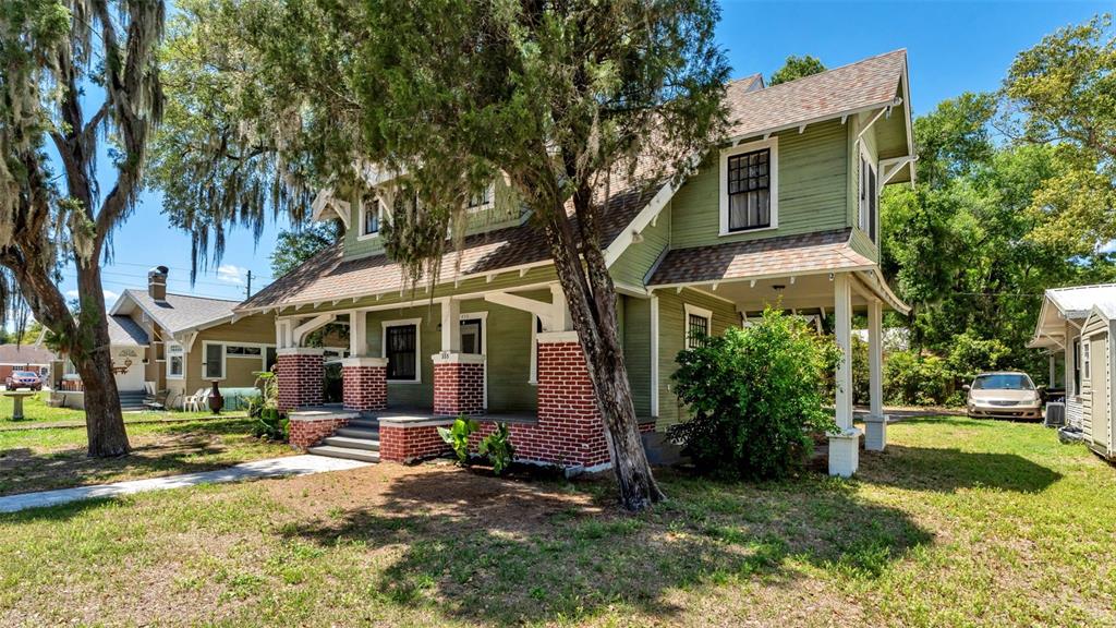 A two-story green house with a brick-based porch stands on a grassy lot — 355 S BROADWAY AVENUE, BARTOW, FL