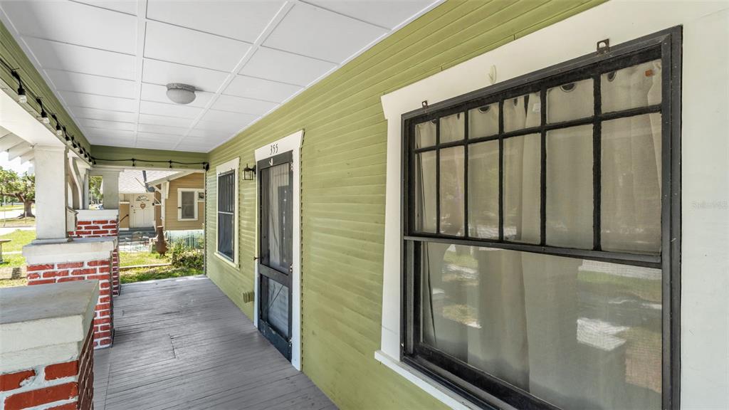 A covered porch with green siding, a brick column, and a window with black trim — 355 S BROADWAY AVENUE, BARTOW, FL