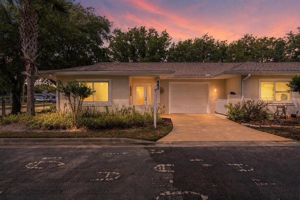 A single-story house with a garage, a front door, and a driveway at sunset — 545 WAYNE AVENUE, NEW SMYRNA BEACH, FL