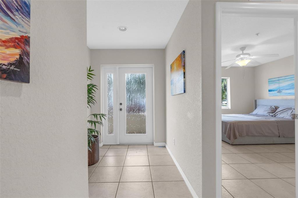A tiled entryway leads to a front door with glass panels, with a bedroom visible nearby — 545 WAYNE AVENUE, NEW SMYRNA BEACH, FL