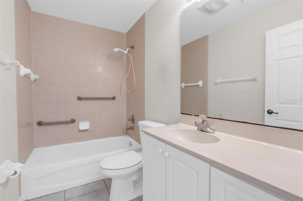 A bathroom features a tub-shower combination with grab bars, a toilet, and a vanity — 545 WAYNE AVENUE, NEW SMYRNA BEACH, FL