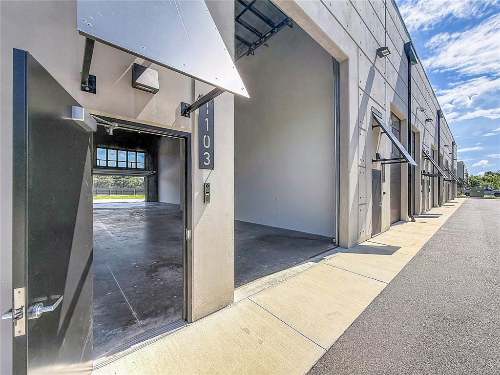 An exterior view of a commercial unit with a metal awning and open garage door — 6500 MOTOR ENCLAVE WAY UNIT #1103, TAMPA, FL
