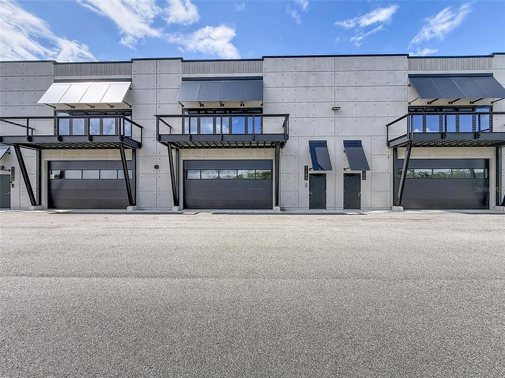 The exterior of a modern commercial building features three garage doors and two metal balconies — 6500 MOTOR ENCLAVE WAY UNIT #1103, TAMPA, FL