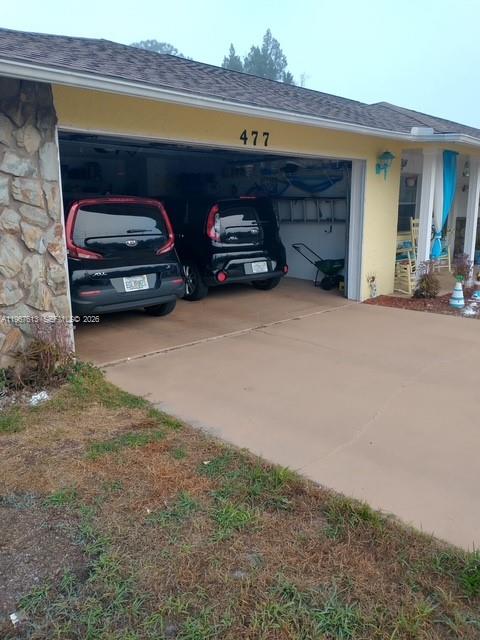 A two-car garage with two black Kia Soul vehicles parked inside a yellow house — 477 W BUTTONBUSH Dr, Citrus Springs FL 34465, CITRUS SPRINGS, FL