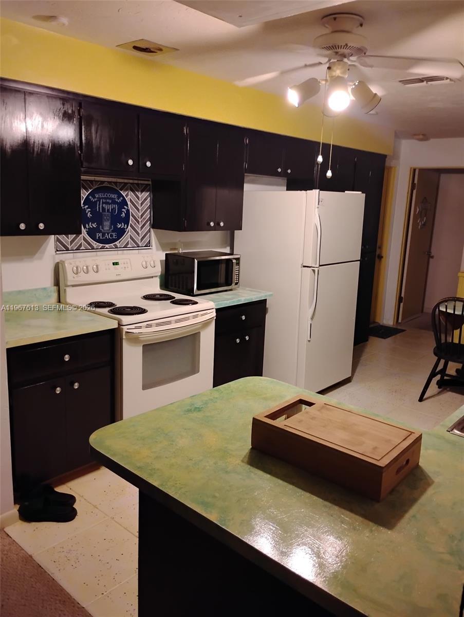 A kitchen features dark cabinets, a white stove, a white refrigerator, and green countertops — 477 W BUTTONBUSH Dr, Citrus Springs FL 34465, CITRUS SPRINGS, FL