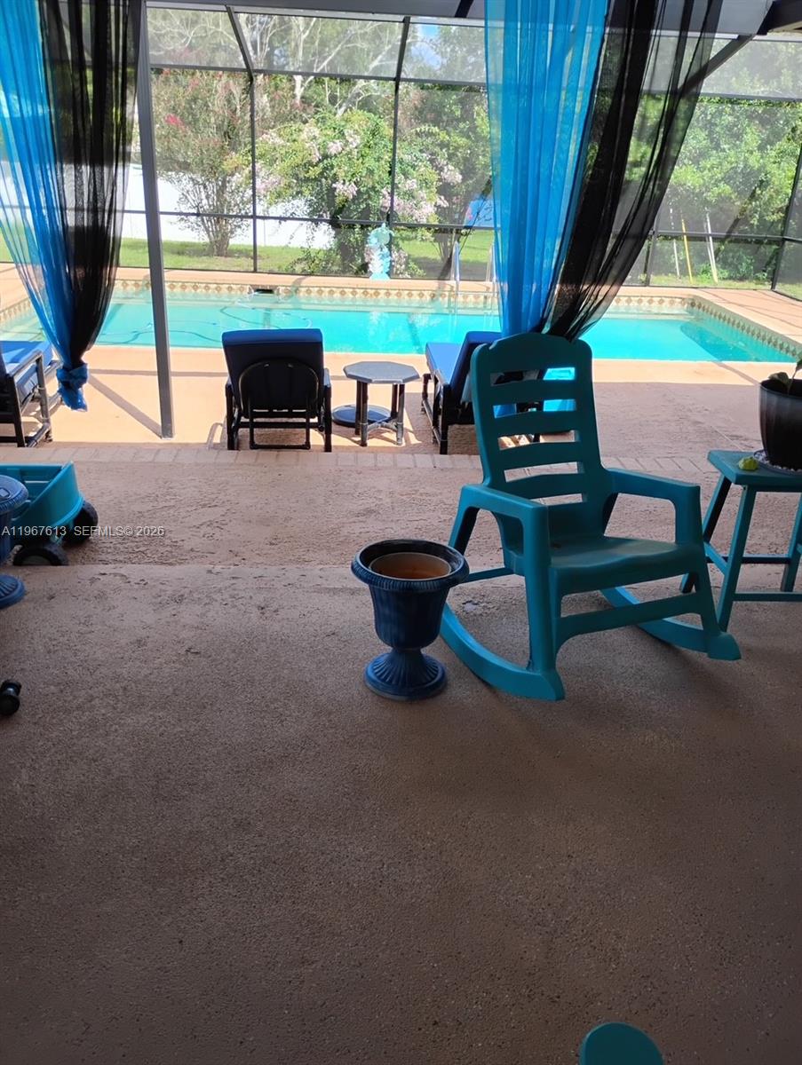 A covered patio features a swimming pool, lounge chairs, and a turquoise rocking chair — 477 W BUTTONBUSH Dr, Citrus Springs FL 34465, CITRUS SPRINGS, FL
