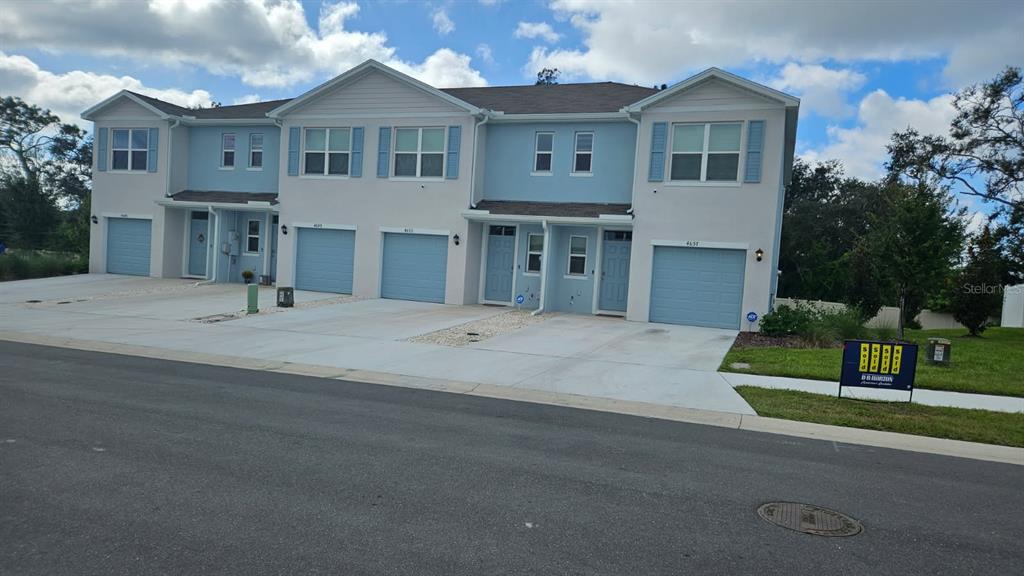A row of light blue two-story townhomes with attached garages and concrete driveways — 4649 PLEASANT AVENUE, PALM HARBOR, FL