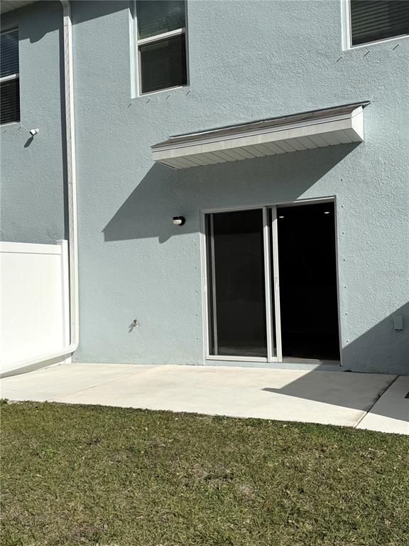 The exterior view shows a light blue stucco wall with a sliding glass door and patio — 4649 PLEASANT AVENUE, PALM HARBOR, FL