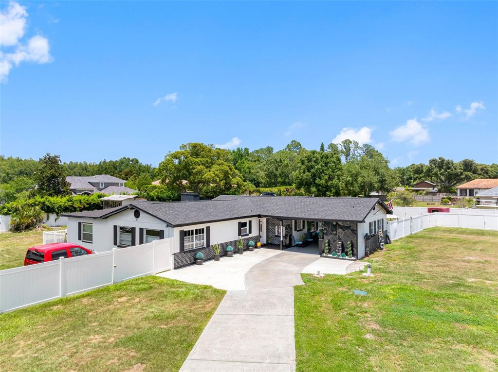 A single-story house with a white exterior, black trim, and a covered carport — 5515 LAKE LE CLARE ROAD, LUTZ, FL